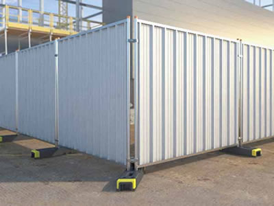 The corner of temporary hoardings in a constructions site. The hoardings are installed with plastic feet.