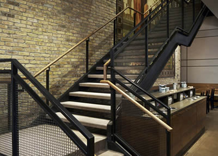 Woven wire cloth infill panels are used as stair railings in the store.